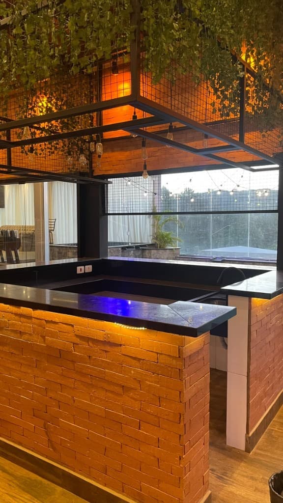 Bar de tijolos com jardim suspenso, iluminação e vista para área externa