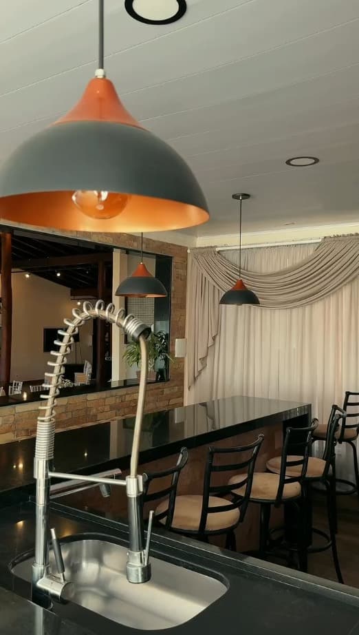 Balcão gourmet com banquetas e luminárias industriais