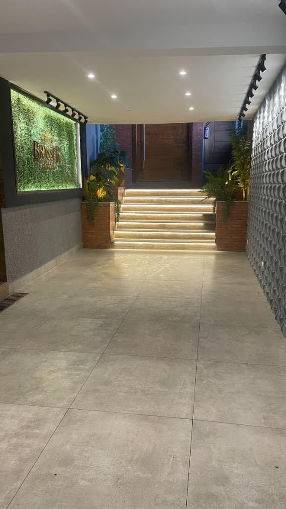 Foyer com parede verde, revestimento geométrico e escada com LED