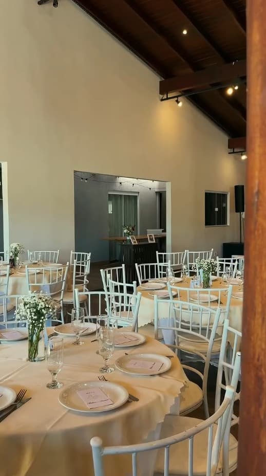 Mesas redondas com toalhas claras e centro de mesa com flores