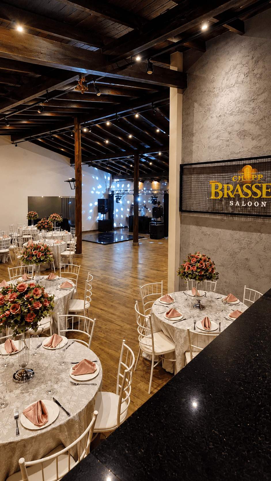 Salão com mesas de rosas, pista de dança e iluminação festiva
